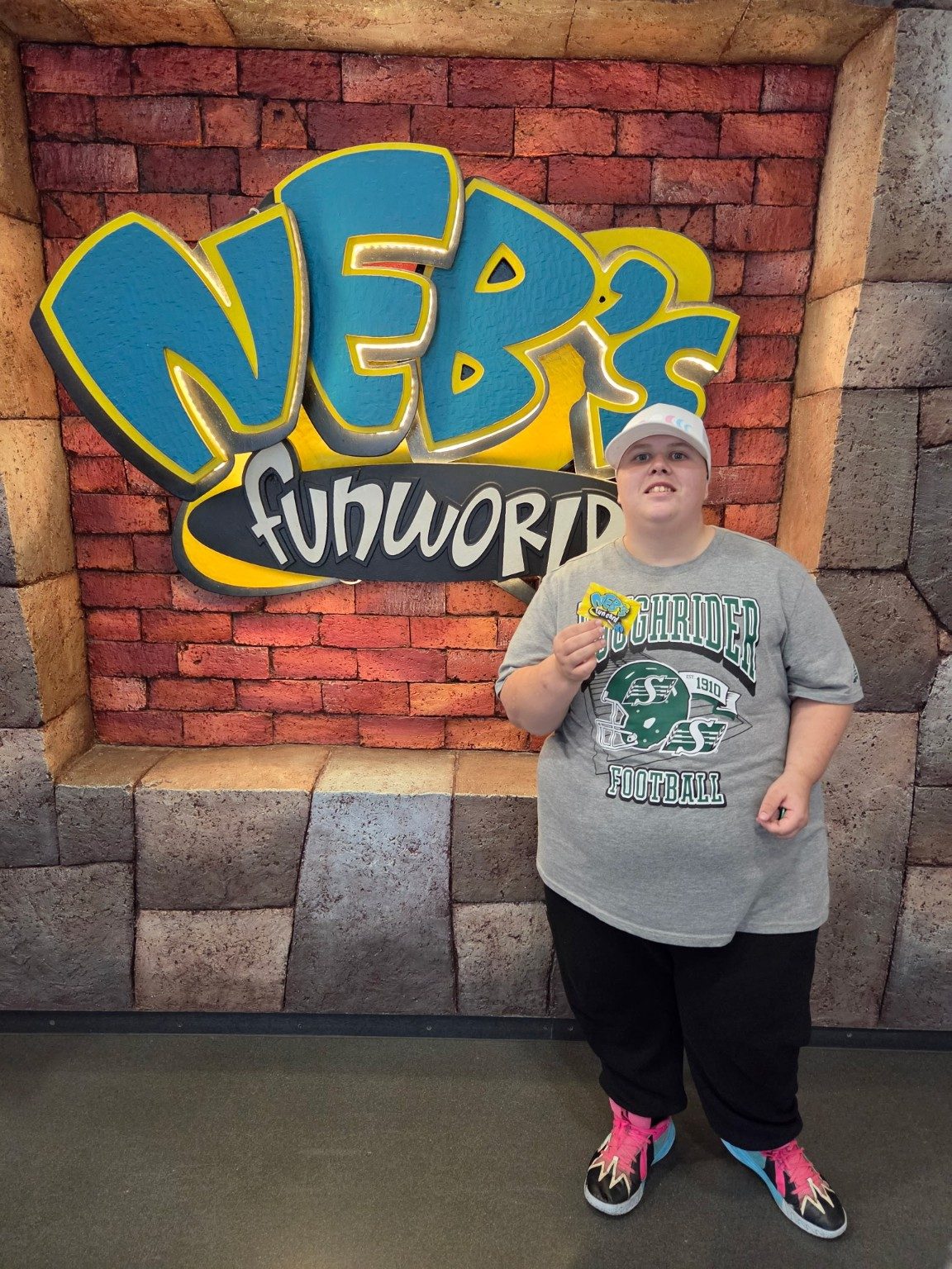 A person smiling in front of an amusement park sign during a community outing